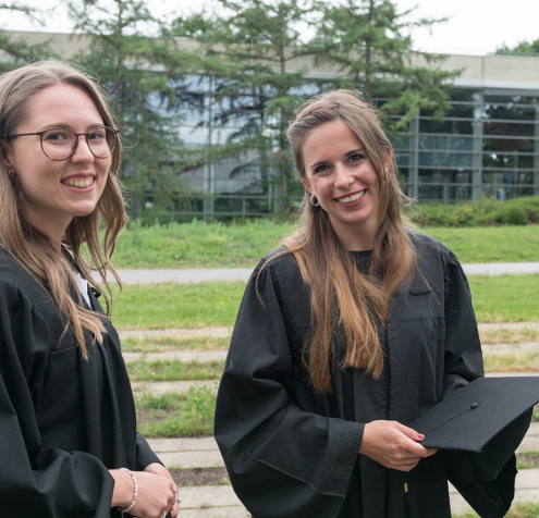 Bachelorstudierende mit Akademikerhut in der Hand